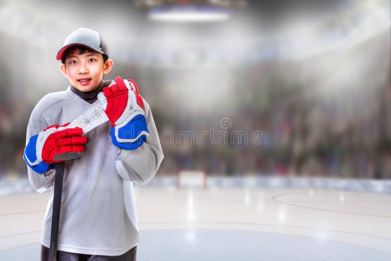 Junior hockey player posing on ice in sports arena with hockey stick. Shallow depth of field on background and copy space. Junior hockey player posing on ice in sports arena with hockey stick. Shallow depth of field on background and copy space.