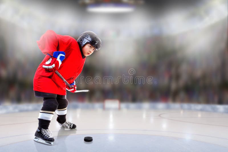 Low angle view of hockey player handling puck on ice with sports arena full of fans in the stands and copy space. Shallow depth of field on background. Low angle view of hockey player handling puck on ice with sports arena full of fans in the stands and copy space. Shallow depth of field on background.