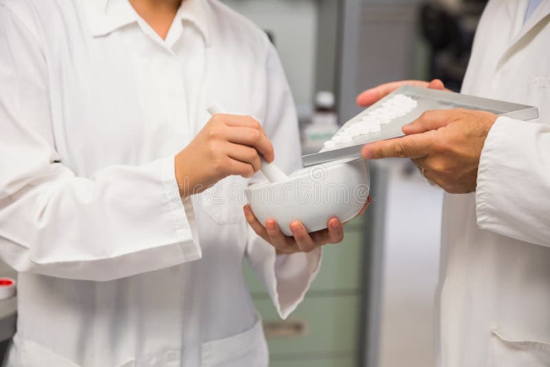 Juniorapotheker, der eine Medizin mit ihrem Senior mischt lizenzfreie stockfotografie Juniorapotheker, der eine Medizin mit ihrem Senior mischt lizenzfreie stockfotografie