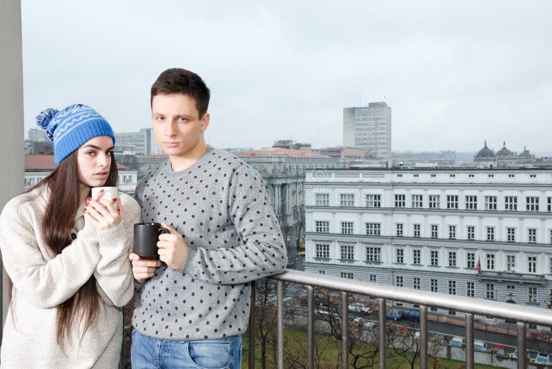 Junte feliz en el amor que abraza cerca de la verja con las tazas de té o de co fotos de archivo Junte feliz en el amor que abraza cerca de la verja con las tazas de té o de co fotos de archivo