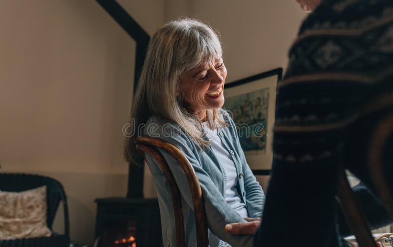 Couple sitting at home talking to each other. Old women laughing while having a conversation with a person at home. Couple sitting at home talking to each other. Old women laughing while having a conversation with a person at home.