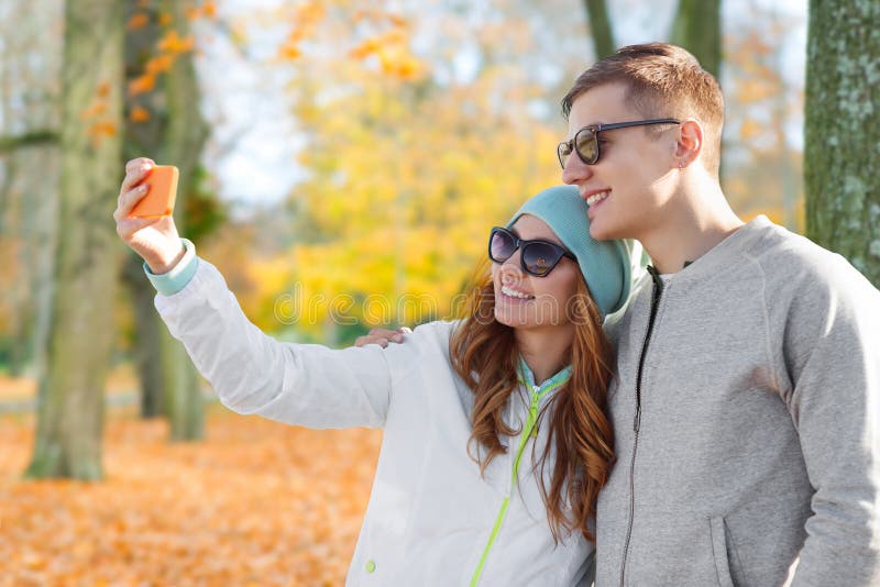 Junte tomar el selfie por smartphone en parque del oto?o imagen de archivo Junte tomar el selfie por smartphone en parque del oto?o imagen de archivo
