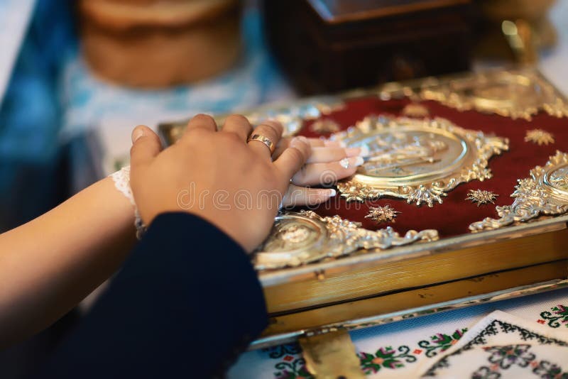 Juramento nos recém-casados na Bíblia luxuriously decorada, nas mãos dos homens e nas mulheres na igreja perto do altar fotografia de stock royalty free Juramento nos recém-casados na Bíblia luxuriously decorada, nas mãos dos homens e nas mulheres na igreja perto do altar fotografia de stock royalty free