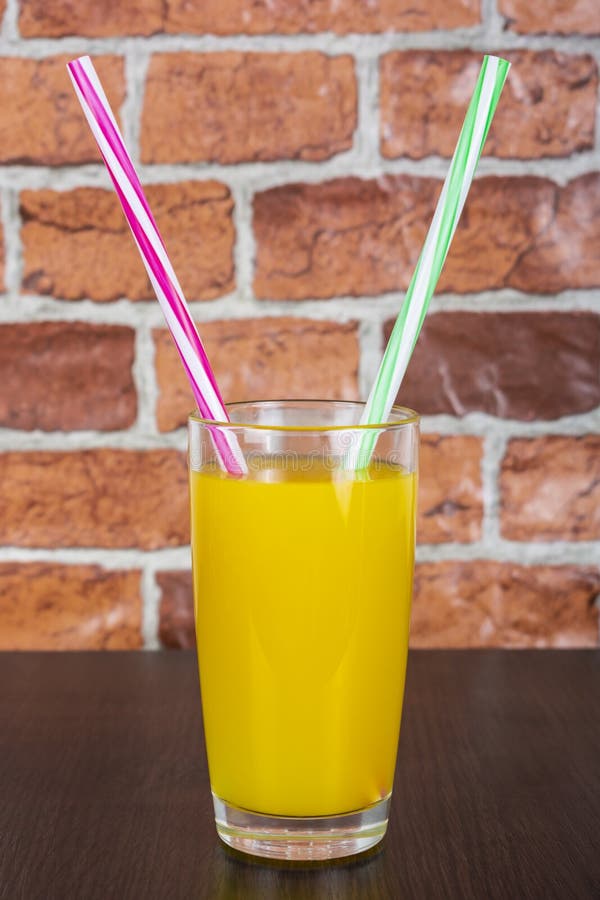 Jus d'orange Twee van het de Gezondheidsconcept van strovitaminen de houten achtergrond en bakstenen muur stock foto Jus d'orange Twee van het de Gezondheidsconcept van strovitaminen de houten achtergrond en bakstenen muur stock foto