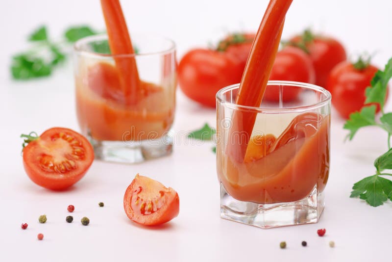 Jus de tomates versant dans un verre sur le blanc photo stock Jus de tomates versant dans un verre sur le blanc photo stock