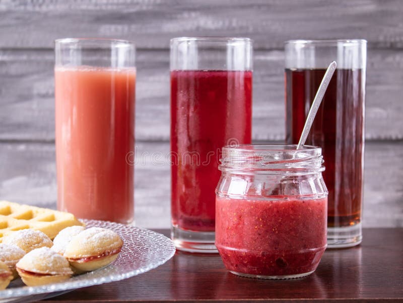 Jus rouge dans un verre à côté d'une cuvette de biscuits et d'un petit pot de confiture images libres de droits Jus rouge dans un verre à côté d'une cuvette de biscuits et d'un petit pot de confiture images libres de droits