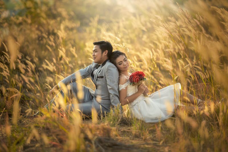 Just married loving hipster couple in wedding dress and suit on field