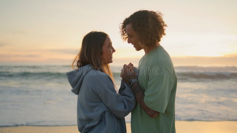 Jóvenes amantes de la puesta de sol en la playa. hombre besando manos amorosas por la noche