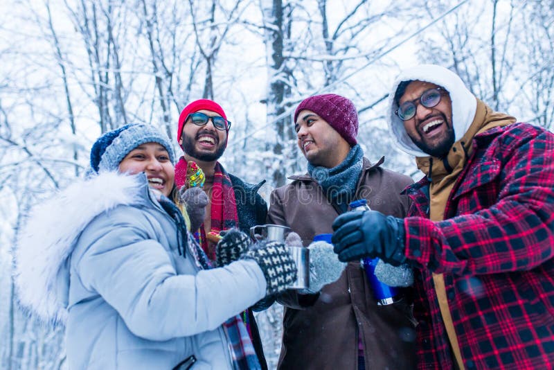 Jóvenes amigos indios felices se calientan con té caliente.