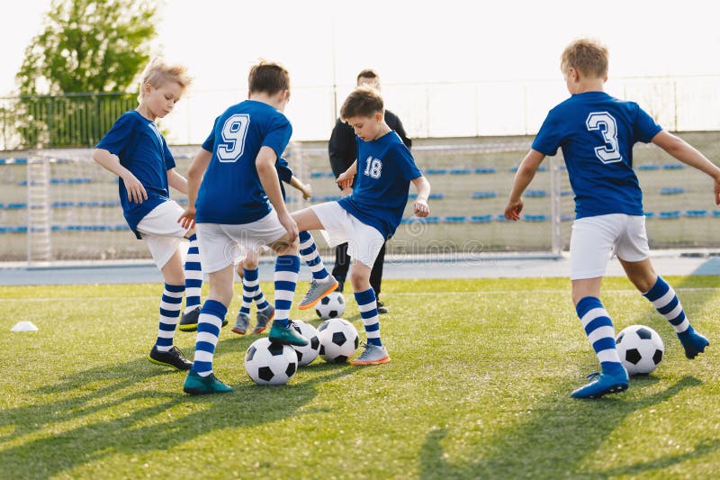 Jóvenes jugando al fútbol. Competencia de práctica de fútbol junior entre los jugadores que corren fotografía de archivo