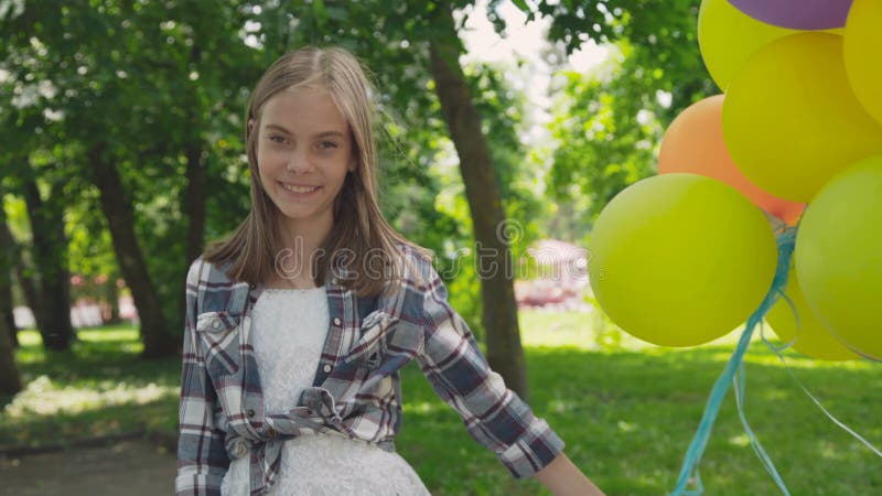 Júbilo feliz de la chica joven con los globos coloridos en un parque 4K metrajes