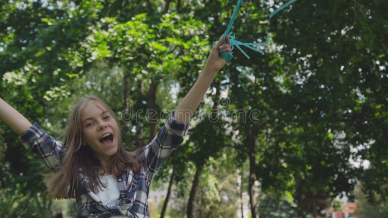 Júbilo feliz de la chica joven y giro con los globos coloridos en un parque almacen de metraje de vídeo