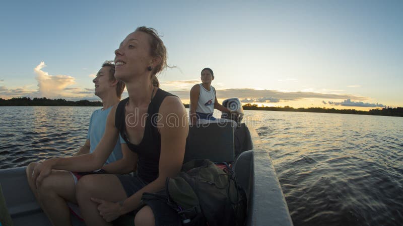 Júntese de los turistas que viajan en canoa en un río en el Amazonas mientras que admira la puesta del sol imagen de archivo libre de regalías Júntese de los turistas que viajan en canoa en un río en el Amazonas mientras que admira la puesta del sol imagen de archivo libre de regalías