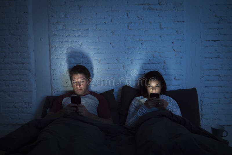 Júntese en casa en cama tarde en la noche usando el teléfono móvil en problema de comunicación de la relación