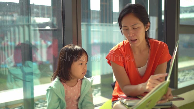 4K Slow motion of asian parent and child reading books at the library