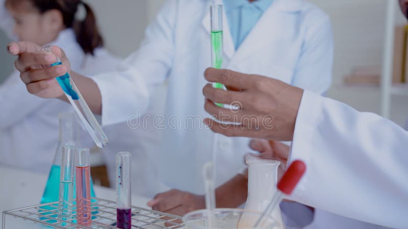 4k fechado de um tubo de teste científico em mãos de um aluno e professor guiando o líquido dentro de uma escola primária branco