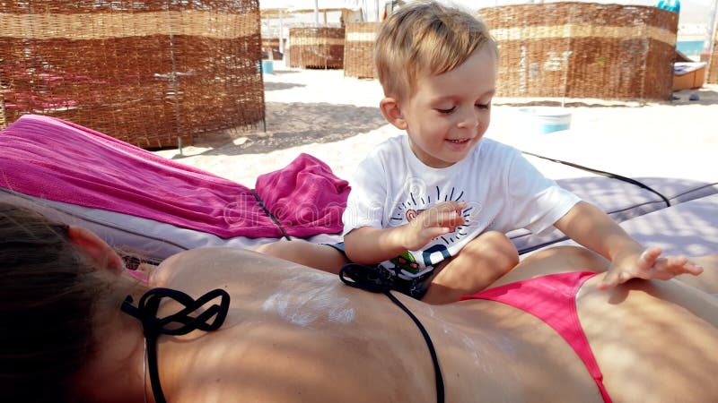 4k Video of Little Toddler Boy Applying Sunscreen Creme on Young Mother Lying on the Sunbed at Sea Beach Stock Footage - Video of girl, beach: 146337116  