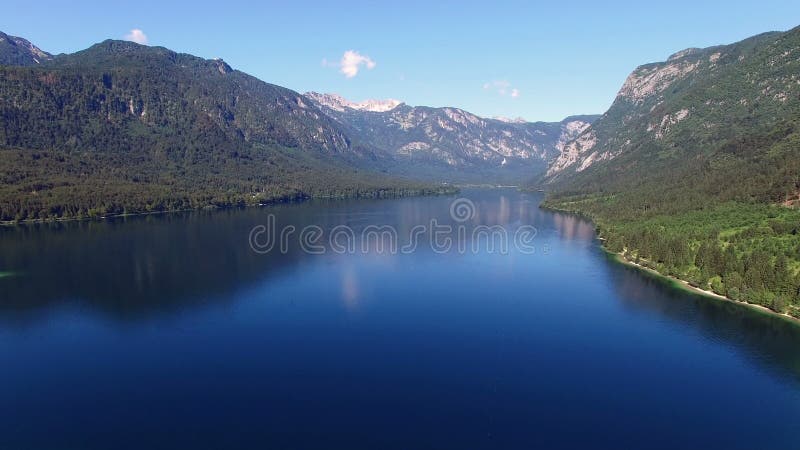 4K. High flight and takeoff above amazing Bohinj Lake in the morning. Blue deep water and Julian Alps mountains. Triglav NP.