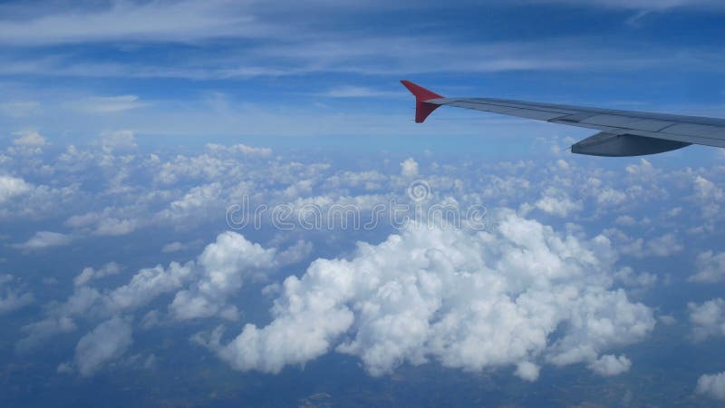 4k lengte Het reizen door de lucht luchtmening door een vliegtuigvenster vleugelvliegtuig en mooie witte wolken in blauwe hemel