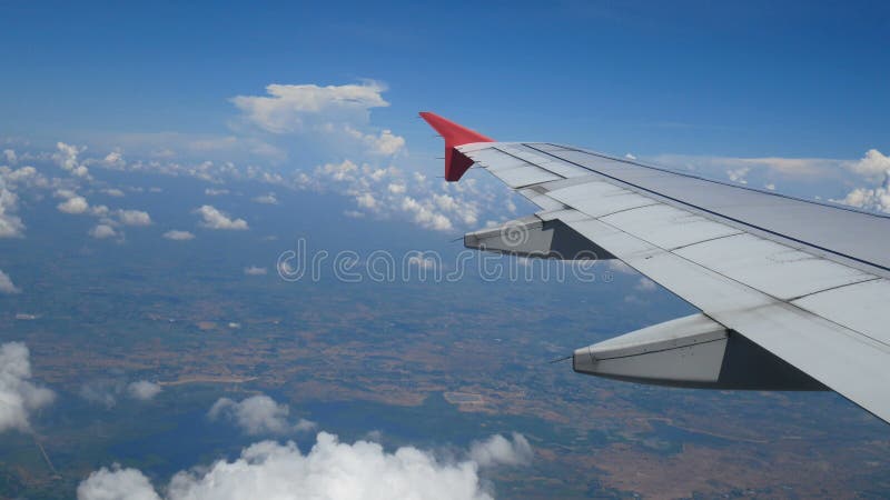 4k lengte Het reizen door de lucht luchtmening door een vliegtuigvenster vleugelvliegtuig en mooie witte wolken in blauwe hemel