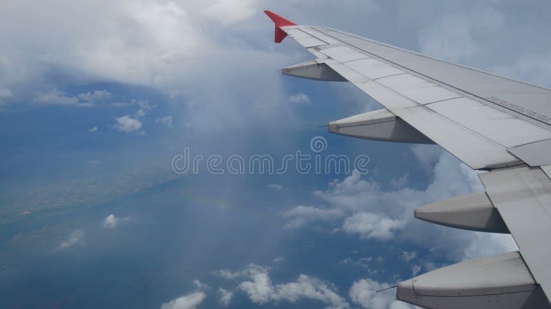 4k lengte vlucht over de regenboog luchtmening door een vliegtuigvenster vleugelvliegtuig en mooie witte wolken in blauwe hemel