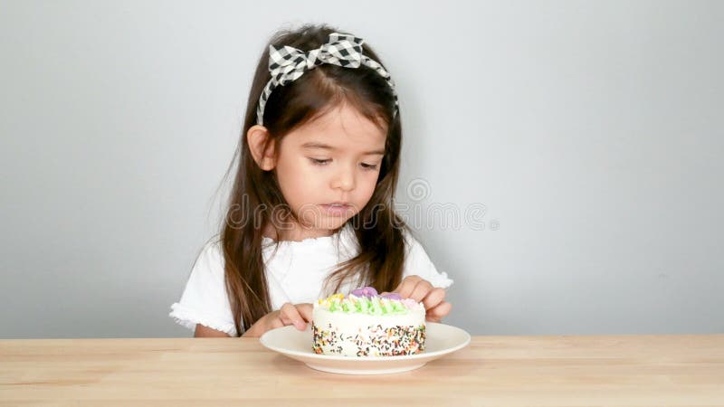 4K longueur, peau adorable de petite fille à manger le gâteau avec ses doigts et sourire avec le visage timide métis modèle l'Asi clips vidéos