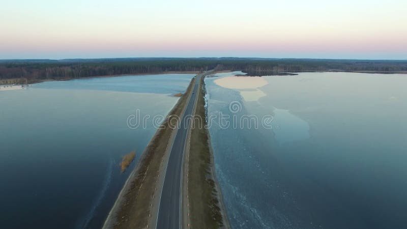 4K Lot nad drogą w zamarzniętej wodzie w zimie na zmierzchu, widok z lotu ptaka