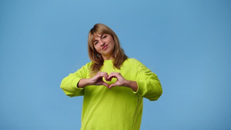4k video di una ragazza che fa la forma del cuore con le mani sul retro blu.