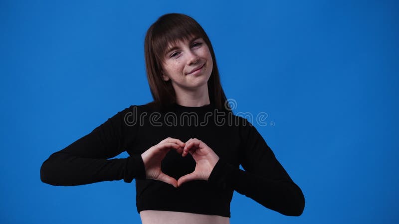 4k video di una ragazza che fa la forma del cuore con le mani sul retro blu.