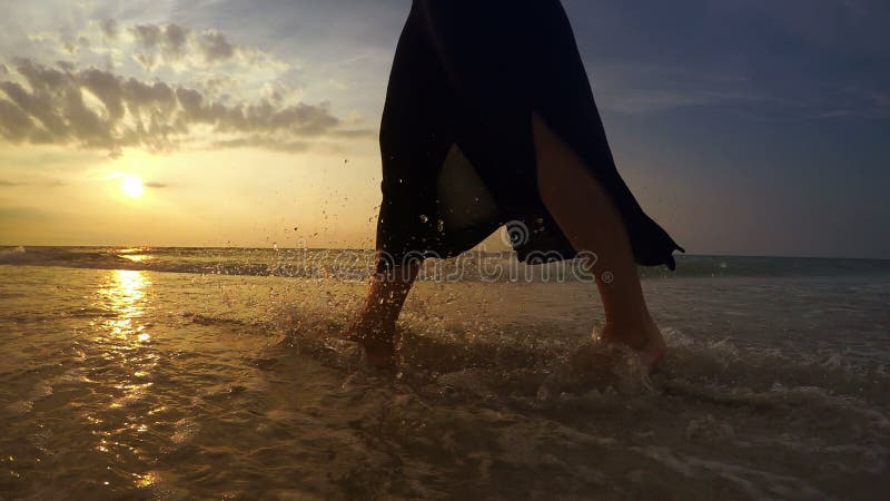 4K video: Woman`s feet while she`s walking along the seacoast