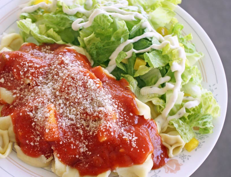 Cheese filled Ravioli with homemade tomato sauce topped with grated Parmesan cheese. Salad with dressing on the side. Cheese filled Ravioli with homemade tomato sauce topped with grated Parmesan cheese. Salad with dressing on the side