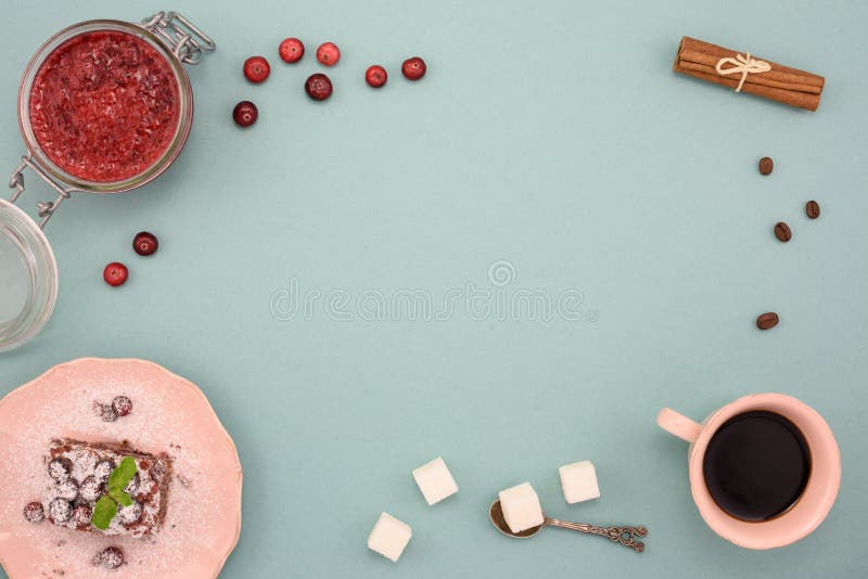Kaffe- och chokladkaka med tranbärdriftstopp och kanel på träbräde, över turkosbakgrund Bästa sikt, kopieringsutrymme royaltyfri bild Kaffe- och chokladkaka med tranbärdriftstopp och kanel på träbräde, över turkosbakgrund Bästa sikt, kopieringsutrymme royaltyfri bild