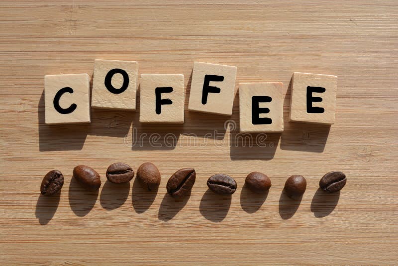 Coffee.  Word in 3d wooden alphabet letters with coffee beans on a bamboo wood background. Coffee.  Word in 3d wooden alphabet letters with coffee beans on a bamboo wood background