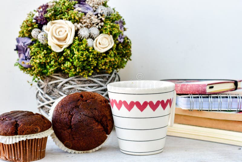 Kaffe och muffin. Koppen kaffe chokladmuffin, tappning bokar, och rosor blommar på vit bakgrund