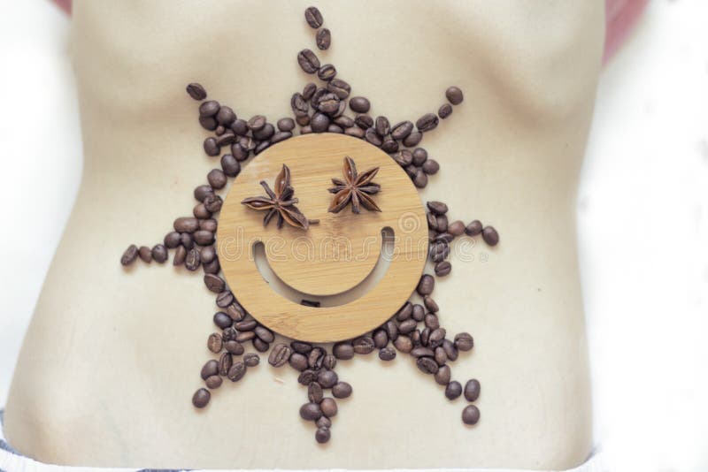 Kaffe är ett sunt och lynne-att förhöja drinken Stjärnasol med ett leende av kaffebönor på buken av en ung flicka Ingen framsida arkivbild Kaffe är ett sunt och lynne-att förhöja drinken Stjärnasol med ett leende av kaffebönor på buken av en ung flicka Ingen framsida arkivbild