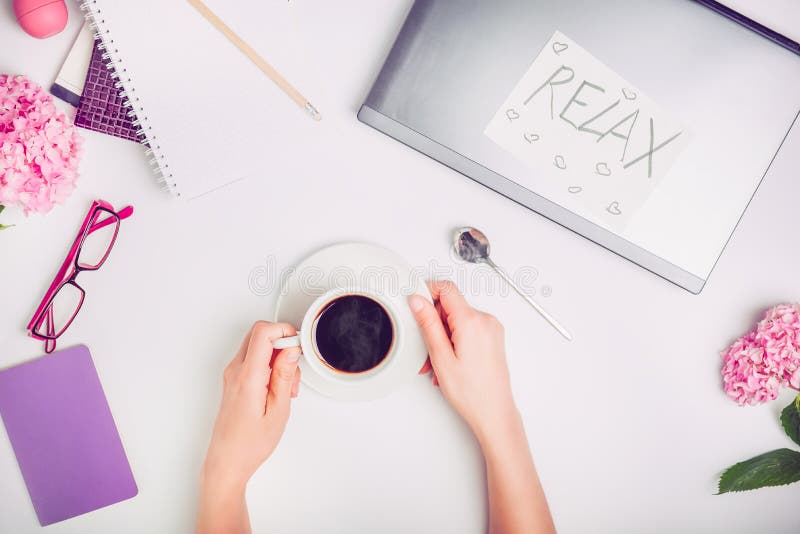 Kaffeeabschaltzeit auf dem Arbeitsplatz - weibliche Hände mit Tasse Kaffee auf dem weißen Arbeitsschreibtisch mit Laptop, Notizbu lizenzfreie stockfotos Kaffeeabschaltzeit auf dem Arbeitsplatz - weibliche Hände mit Tasse Kaffee auf dem weißen Arbeitsschreibtisch mit Laptop, Notizbu lizenzfreie stockfotos