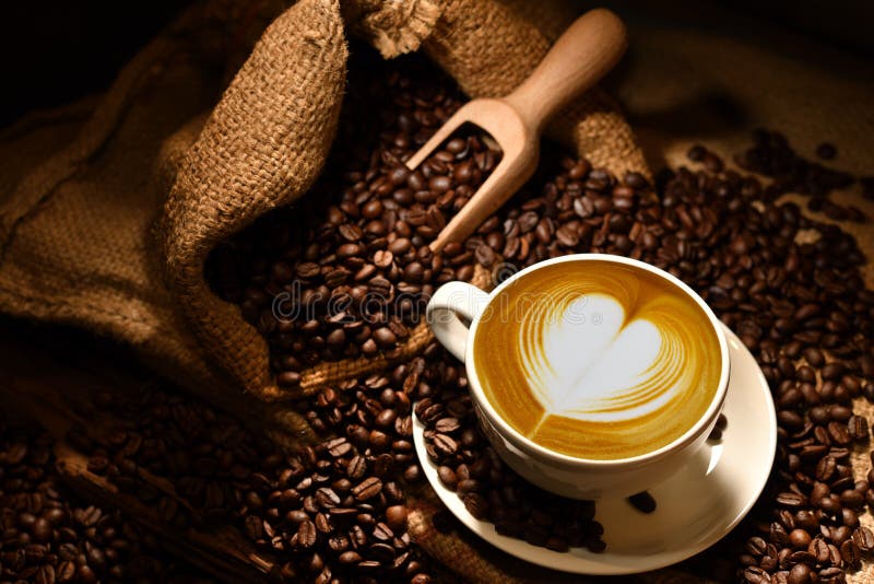 Kaffeetasse mit Herzform und Kaffeebohnen auf altem Holzboden