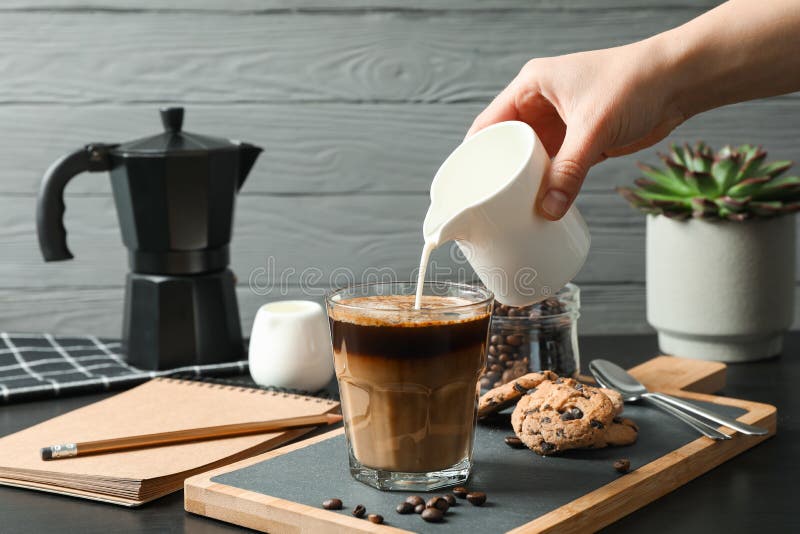 Kaffeezeitzusätze mit der weiblichen Hand auf schwarzer Tabelle gegen grauen Hintergrund, Raum für Text lizenzfreie stockfotos