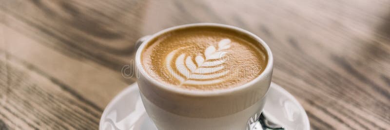 Kaffekopp med latte-konst på cafét-träbordsbanderoamas bakgrund arkivfoto