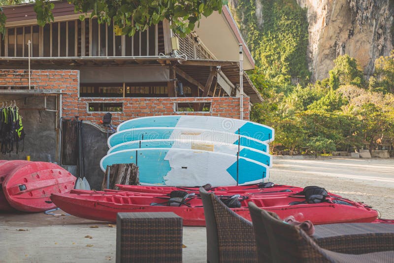 Kajaks und schwimmende Bretter auf dem sandigen Strand früh morgens Schwimmwesten hängen nach links Wassersportausrüstungsverleih stockfoto Kajaks und schwimmende Bretter auf dem sandigen Strand früh morgens Schwimmwesten hängen nach links Wassersportausrüstungsverleih stockfoto
