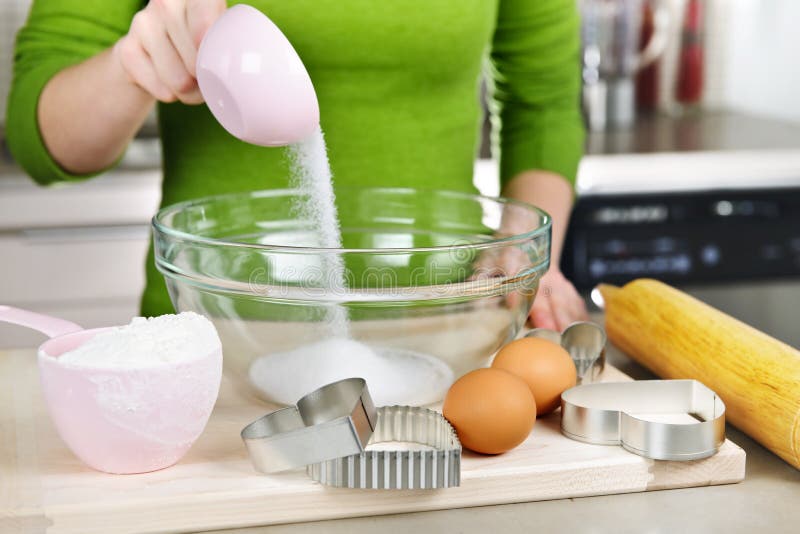 Pouring sugar into mixing bowl with ingredients for making cookies. Pouring sugar into mixing bowl with ingredients for making cookies