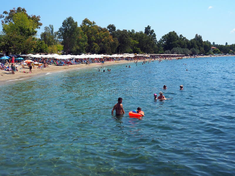 Kala Nera Beach Grekland. Den populära Kala Nera Good Water Beach, en semesterortstad på västkusten av den Pelion halvön, Grekland, med simmare och strandparaplyer och stolar