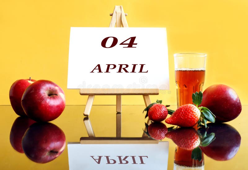 Calendar for April 4: an easel with the inscription 04, april, apples and strawberries next to it, a glass of freshly squeezed juice, yellow background, side view. Calendar for April 4: an easel with the inscription 04, april, apples and strawberries next to it, a glass of freshly squeezed juice, yellow background, side view.
