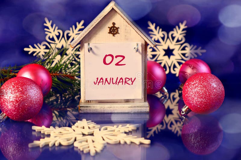 Calendar for January 2: decorative house with the name of the month January, number 02, pink Christmas balls, decorative snowflakes on a blue background, bokeh. Calendar for January 2: decorative house with the name of the month January, number 02, pink Christmas balls, decorative snowflakes on a blue background, bokeh.
