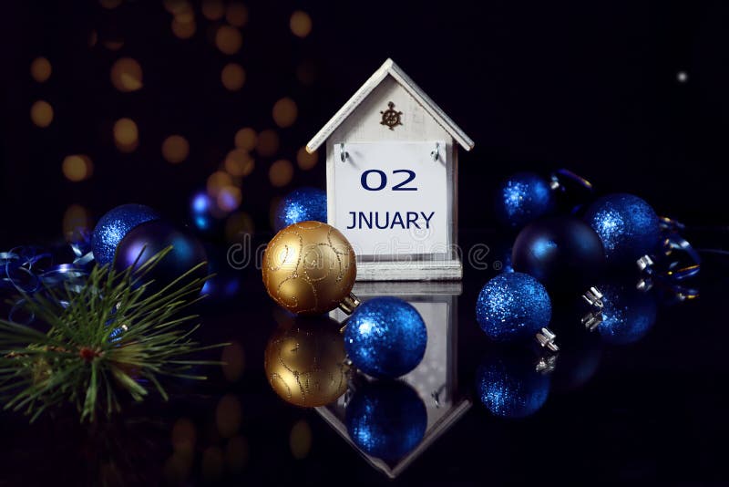 Calendar for January 2: decorative house with the name of the month January, numbers 02 among colorful Christmas balls on a dark background, bokeh. Calendar for January 2: decorative house with the name of the month January, numbers 02 among colorful Christmas balls on a dark background, bokeh.