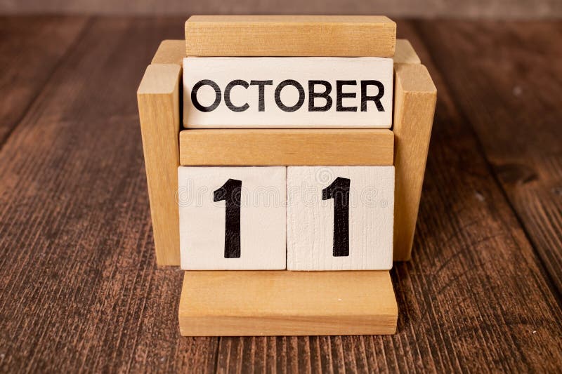 White block calendar present date 11 and month October on wood background. White block calendar present date 11 and month October on wood background