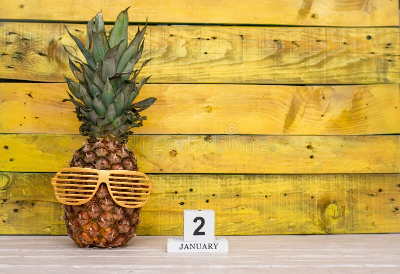 Creative planner calendar january with number 2. Pineapple character on bright yellow summer wooden background with calendar cubes. Creative planner calendar january with number 2. Pineapple character on bright yellow summer wooden background with calendar cubes