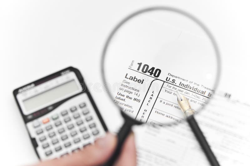 Accountant looking through a magnifying glass and calculating taxes with a calculator. Accountant looking through a magnifying glass and calculating taxes with a calculator