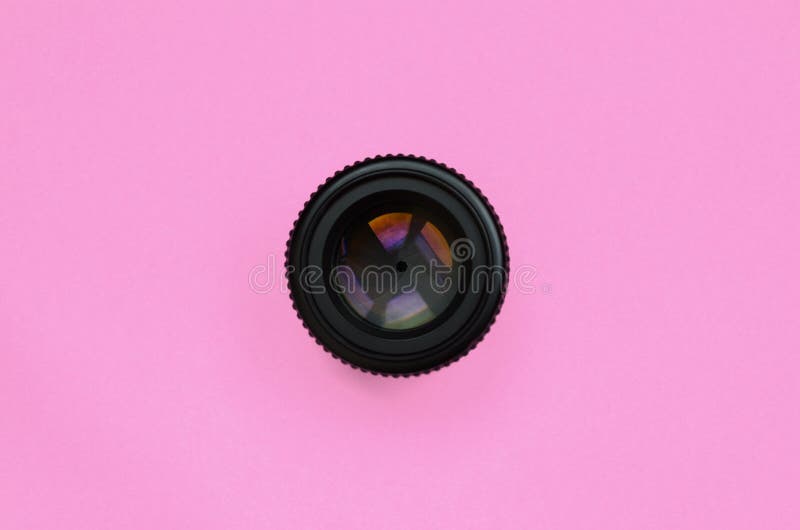 Kameralins med en stängd öppningslögn på texturbakgrund av pastellfärgat rosa färgpapper för mode i minsta begrepp