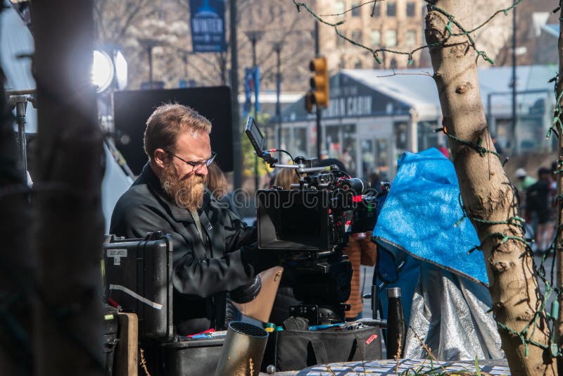 Kameraman som justerar hans kamera på platsen av filmandet av en reklamfilm arkivbilder Kameraman som justerar hans kamera på platsen av filmandet av en reklamfilm arkivbilder